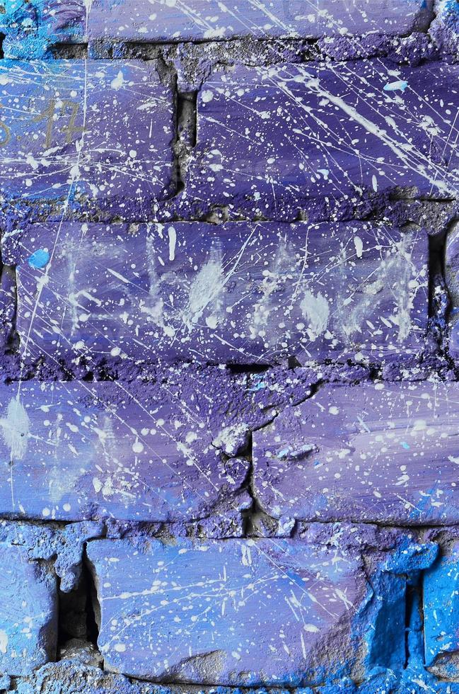 The texture of the old brick wall, painted in blue and purple colors with carelessly spaced white drops and splashes that visualize the stars in outer space photo