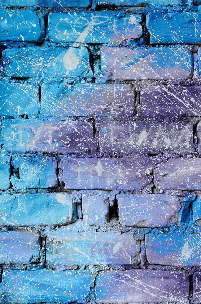 The texture of the old brick wall, painted in blue and purple colors with carelessly spaced white drops and splashes that visualize the stars in outer space photo