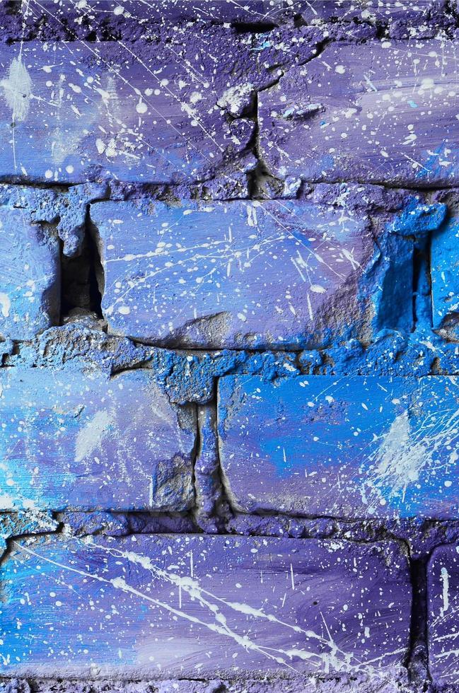 la textura de la antigua pared de ladrillo, pintada en colores azul y púrpura con gotas blancas descuidadamente espaciadas y salpicaduras que visualizan las estrellas en el espacio ultraterrestre foto