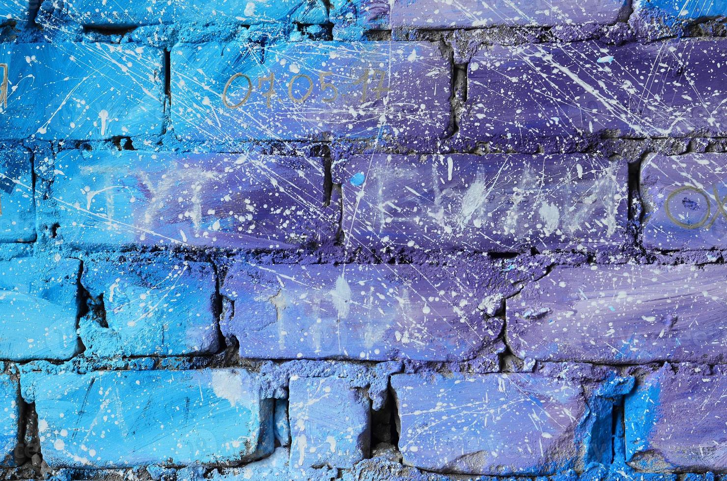 la textura de la antigua pared de ladrillo, pintada en colores azul y púrpura con gotas blancas descuidadamente espaciadas y salpicaduras que visualizan las estrellas en el espacio ultraterrestre foto