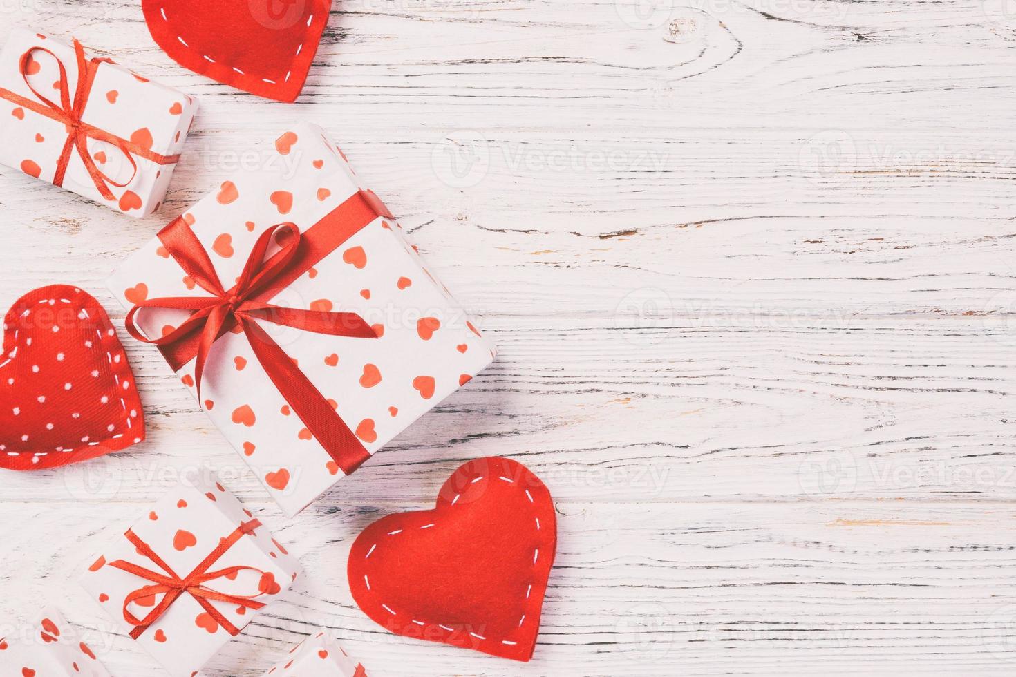 Valentine or other holiday handmade present in paper with red hearts and gifts box in holiday wrapper. Present box of gift on white wooden table top view with copy space, empty space for design photo