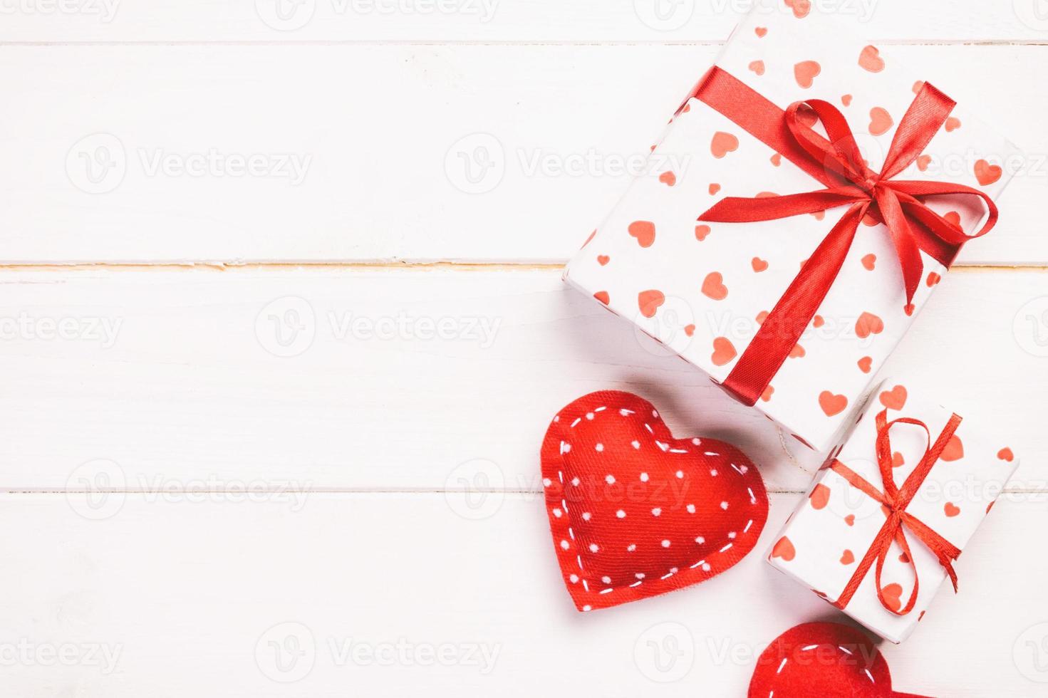 Valentine or other holiday handmade present in paper with red hearts and gifts box in holiday wrapper. Present box gift on white wooden table top view with copy space, empty space for design photo
