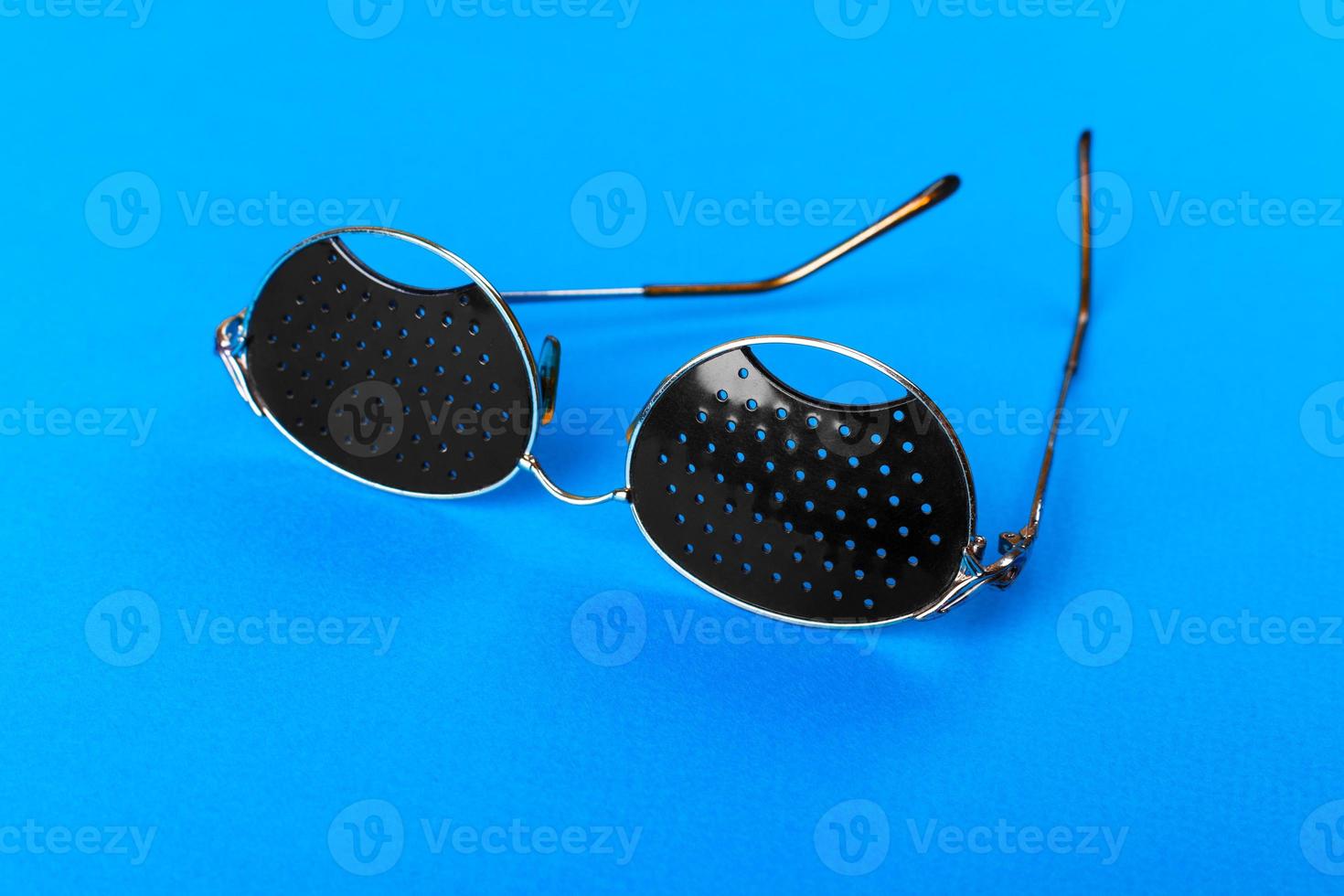 Two different type of glasses on blue background. Medical concept. Top view. Pinhole black eyeglasses help relaxing weary eyes Isolated on white background. Classic Fashion optical eyeglasses photo