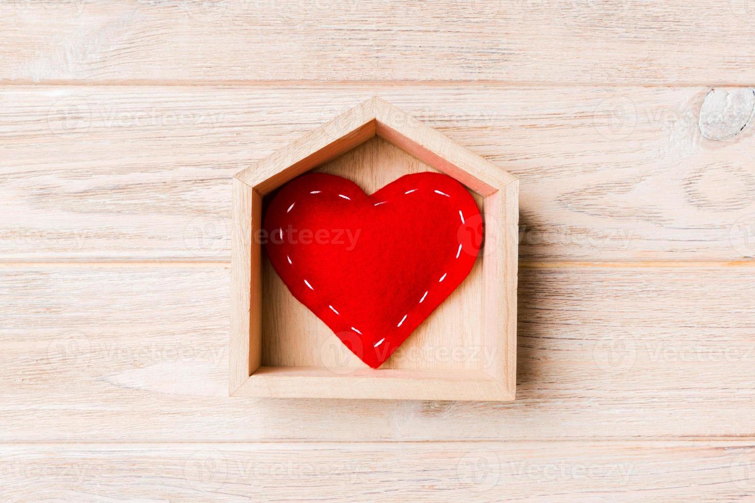 Top view of red textile heart in a house on wooden background. Home sweet home concept. Valentine's day photo