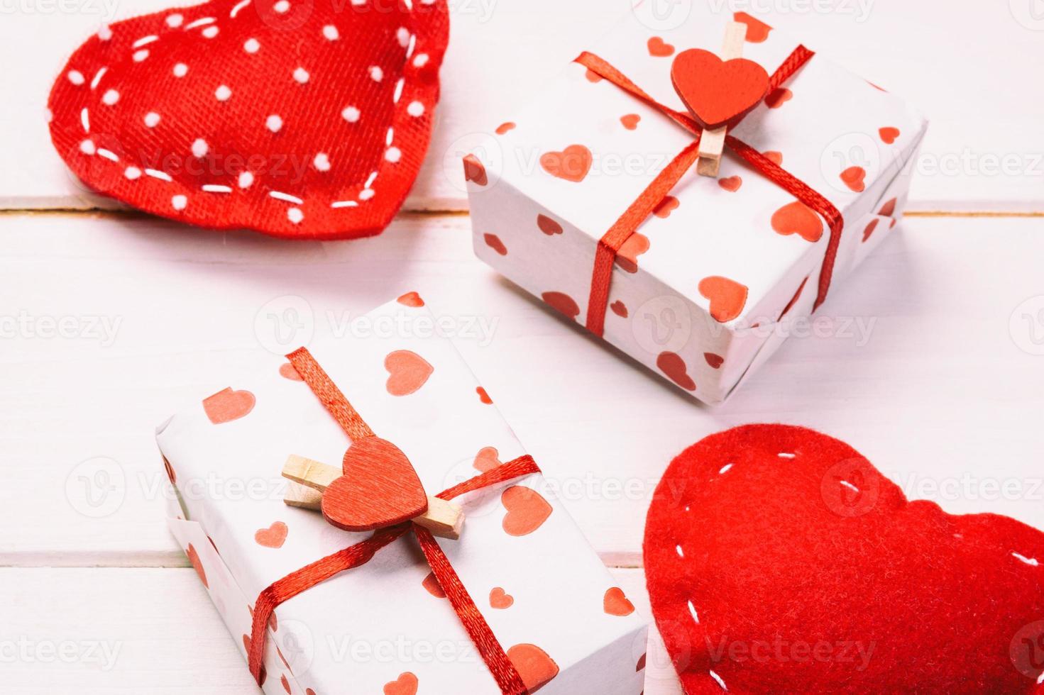 Valentine or other holiday handmade present in paper with red hearts and gifts box in holiday wrapper. Present box gift on white wooden table top view with copy space, empty space for design photo