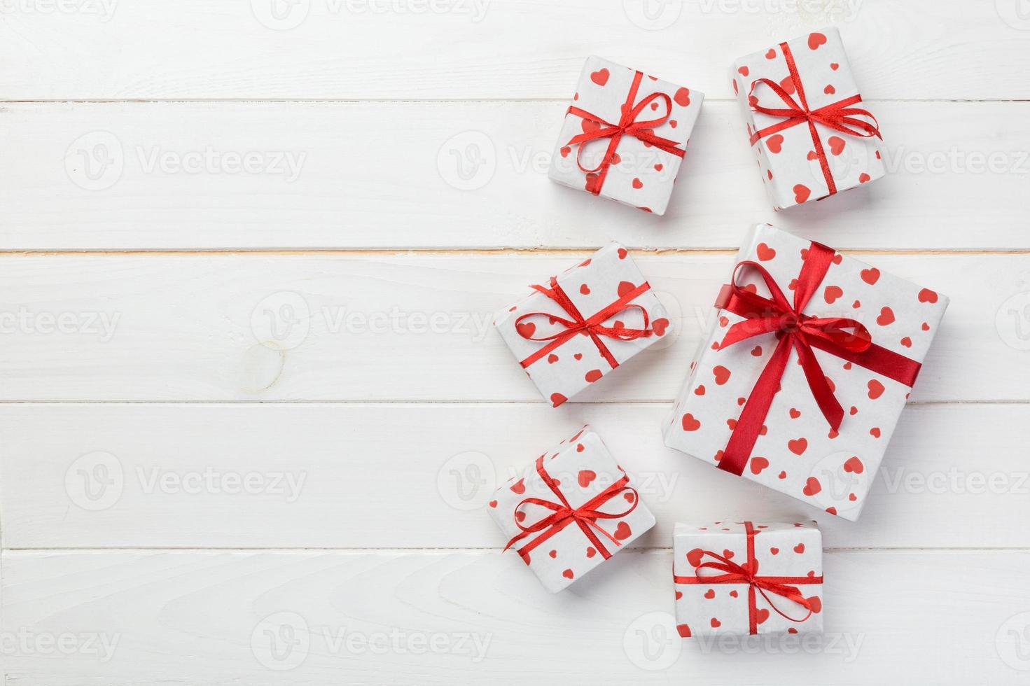 Valentine or other holiday handmade present in paper with red hearts and gifts box in holiday wrapper. Present box gift on white wooden table top view with copy space, empty space for design photo