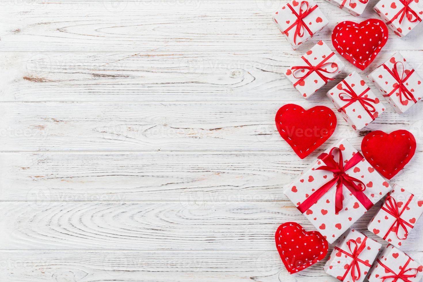 Valentine or other holiday handmade present in paper with red hearts and gifts box in holiday wrapper. Present box of gift on white wooden table top view with copy space, empty space for design photo