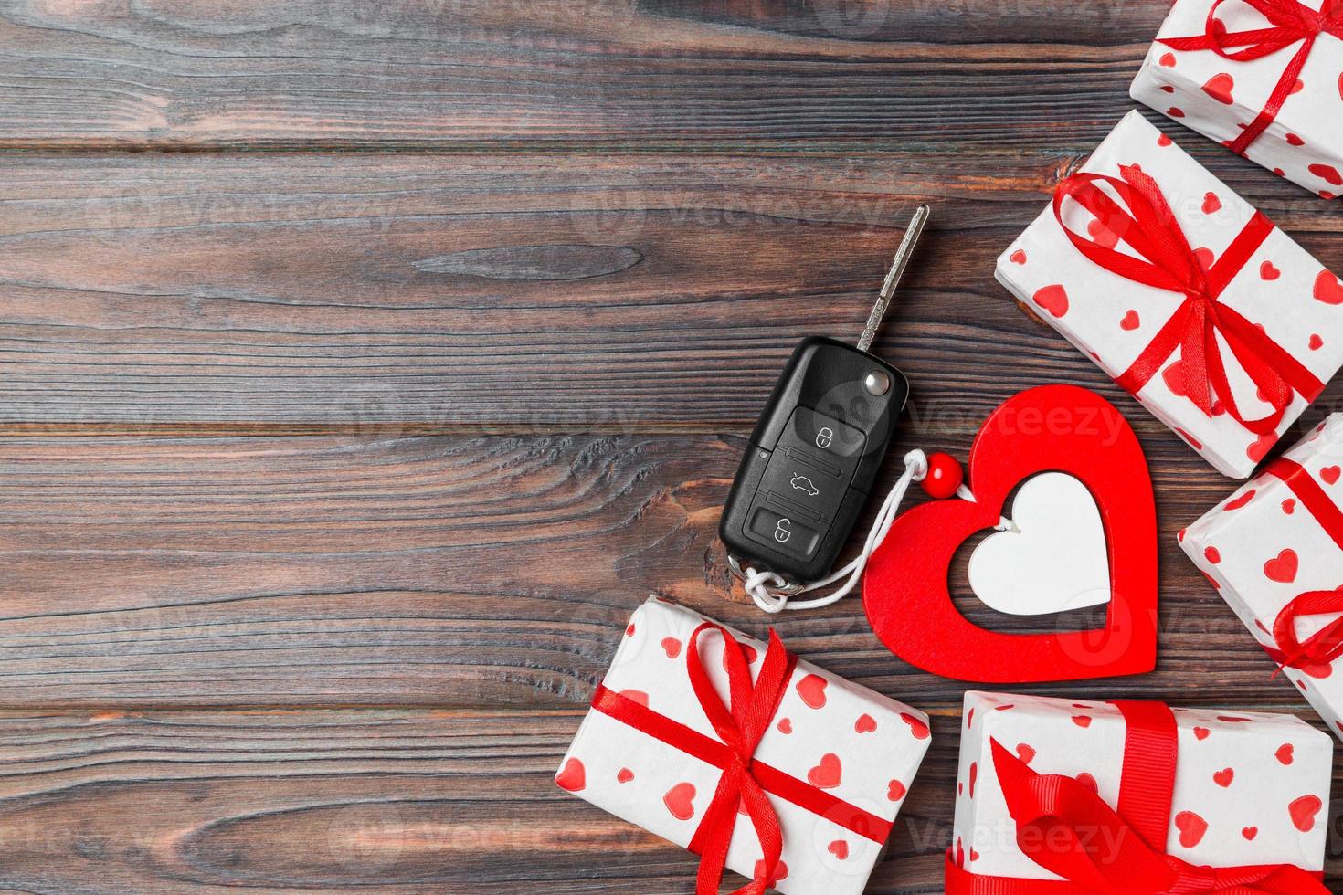 Top view of a present for Valentine's Day on wooden background. Car key, gift boxes and heart with copy space. Surprise concept for a holiday photo