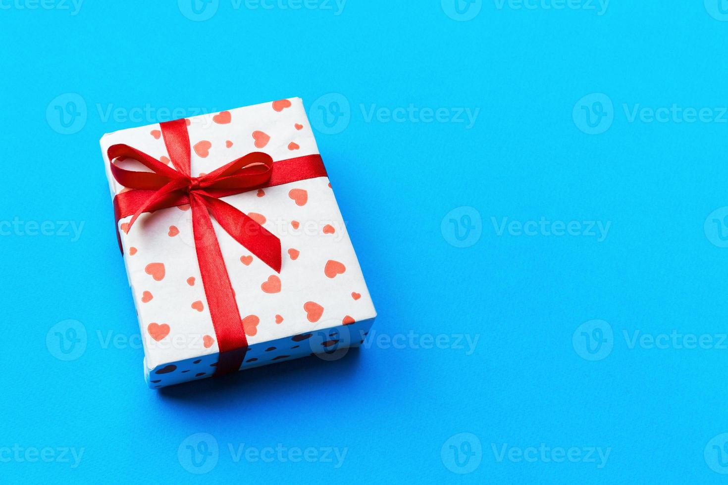 Background with gift box and hearts on blue Background. Top view with copy space for text photo