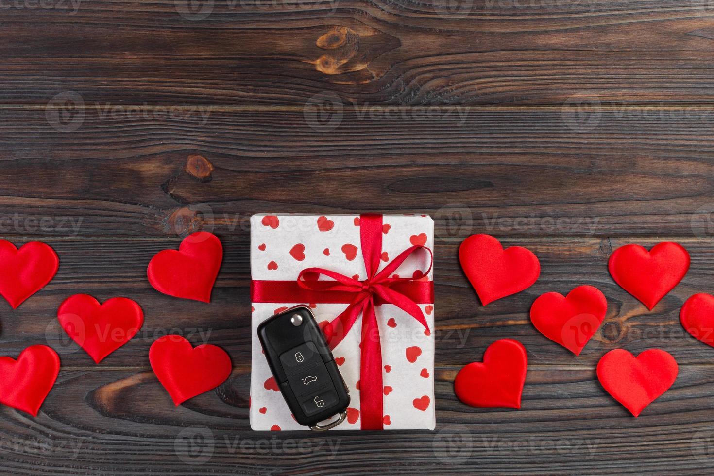 Valentine or other holiday handmade present in paper with red hearts, car keys and gifts box in holiday wrapper. box gift on Dark wooden table top view with copy space, empty space for design photo
