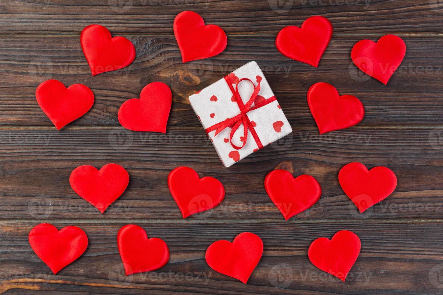 Valentine or other holiday handmade present in paper with red hearts and gifts box in holiday wrapper. Present box of gift on Dark wooden table top view with copy space, empty space for design photo