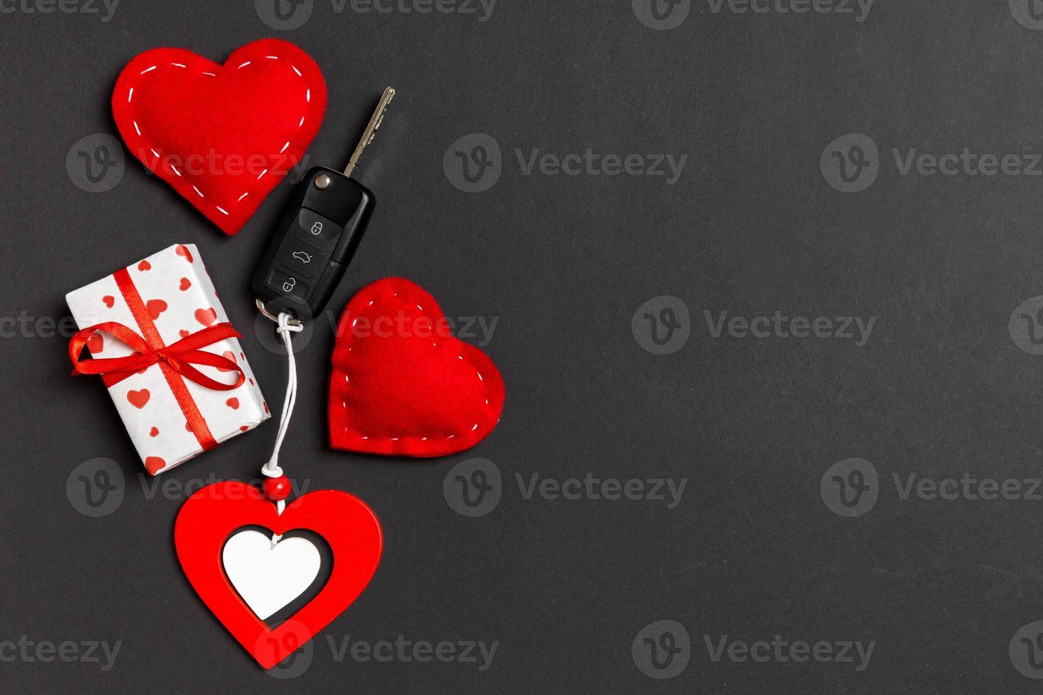 Top view of gift box, car key, wooden and textile heart on colorful background. Luxury present for Valentine's day photo