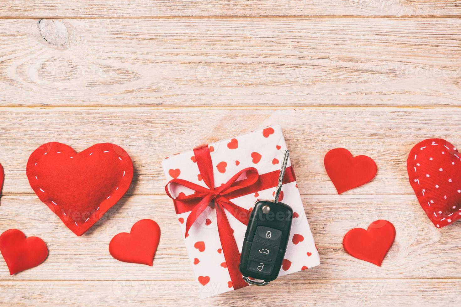 Valentine or other holiday handmade present in paper with red hearts, car keys and gifts box in holiday wrapper. box gift on orange wooden table top view with copy space, empty space for design photo