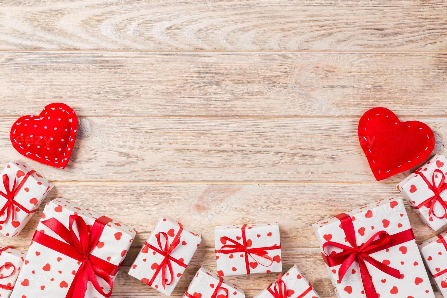 Valentine or other holiday handmade present in paper with red hearts and gifts box in holiday wrapper. Present box of gift on orange wooden table top view with copy space, empty space for design photo