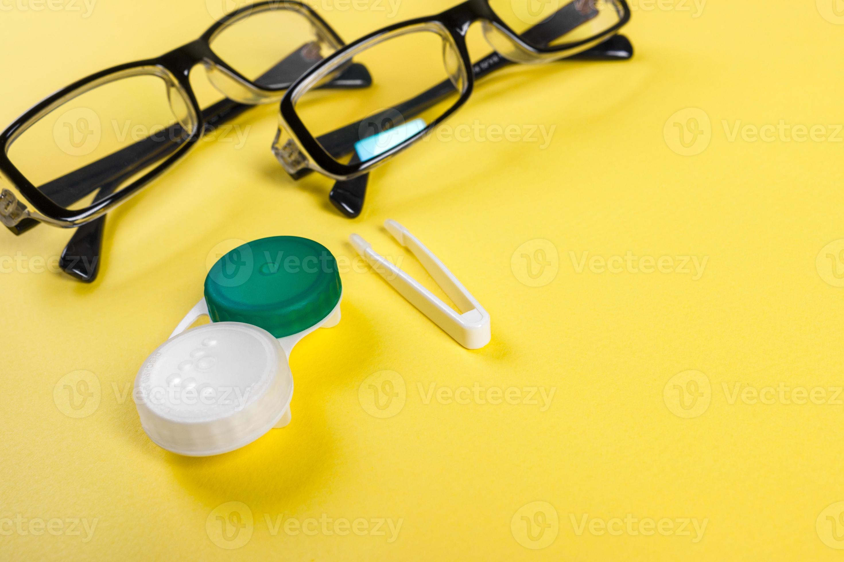 Contact lenses set with plastic case and tweezers with glasses on the background plan on a lilac