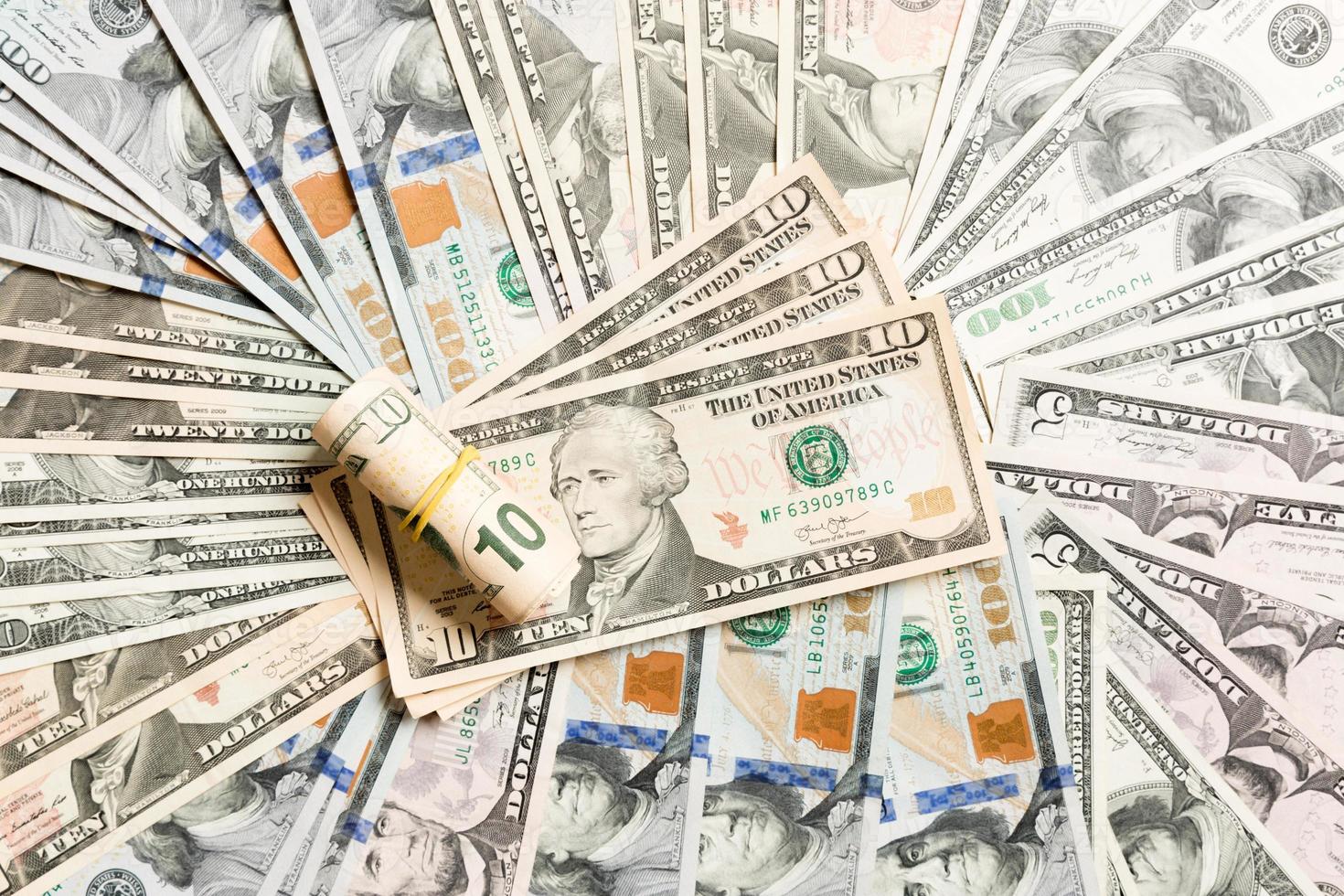 primer plano de un montón de billetes de 10 dólares en el fondo hecho con diferentes billetes de dólar. vista superior del concepto financiero foto