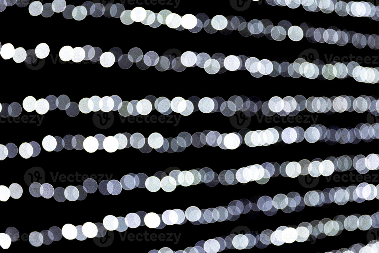 Bokeh de chispa de brillo abstracto desenfocado sobre fondo negro. muchas luces redondas en el fondo foto