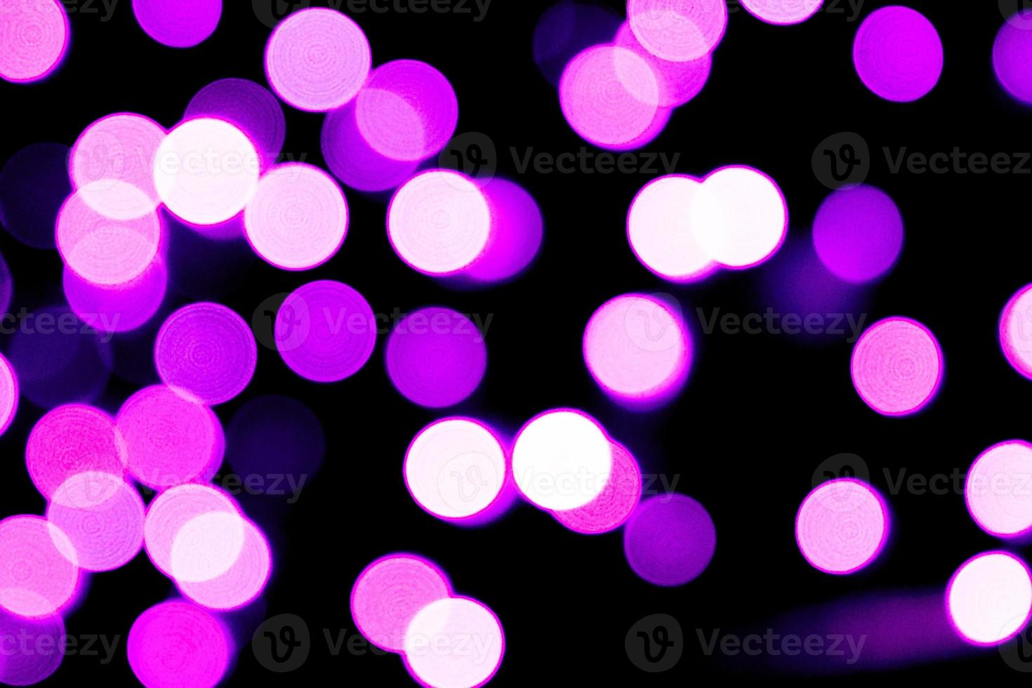 Unfocused abstract purple bokeh on black background. defocused and blurred many round light photo