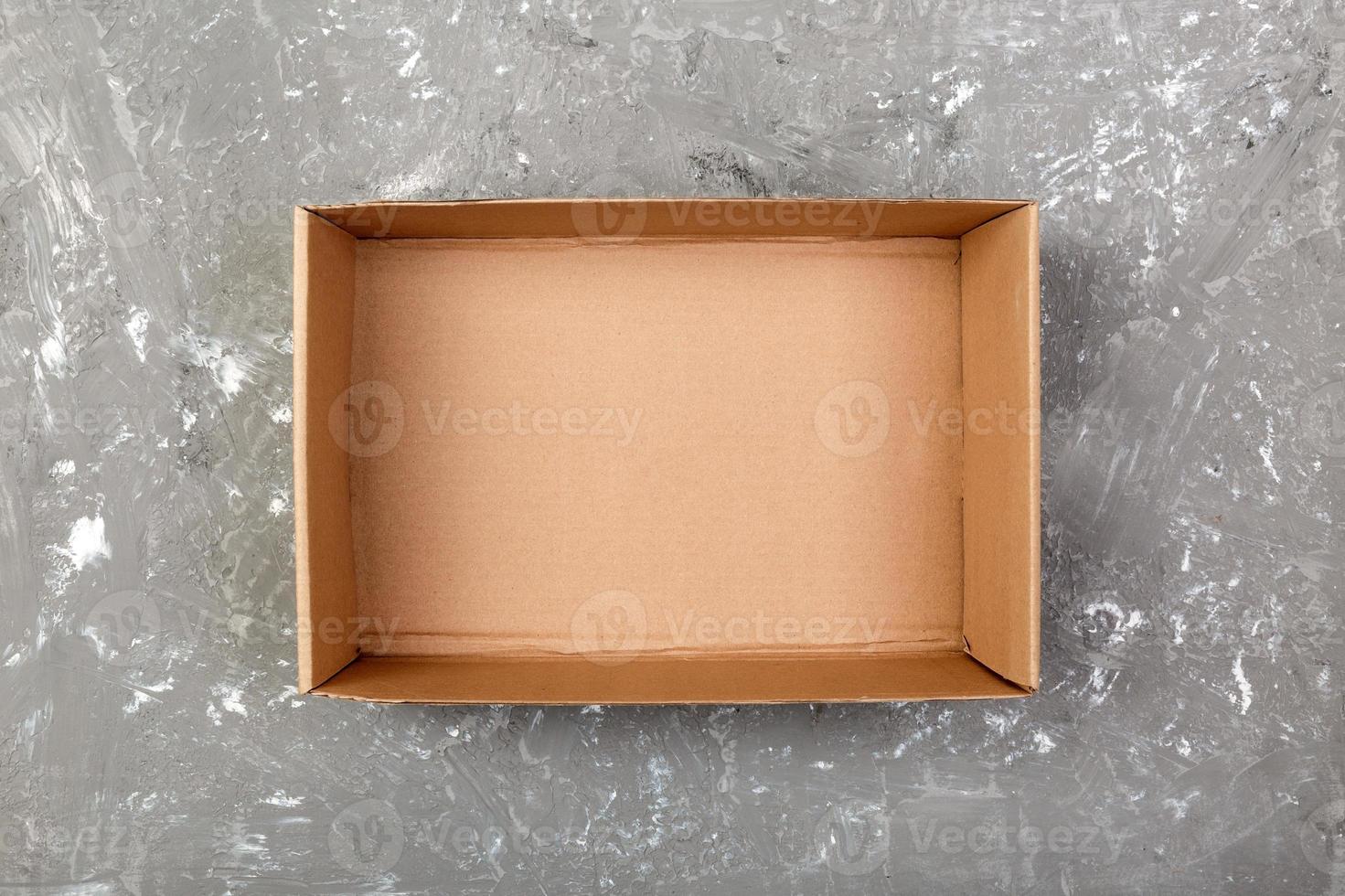 Opened brown blank cardboard box on cement gray background, top view photo