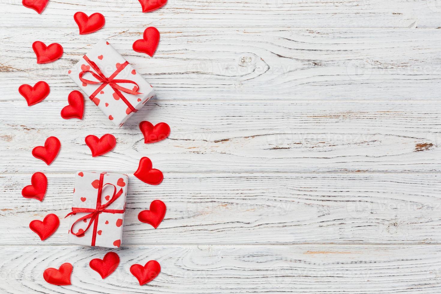 Valentine or other holiday handmade present in paper with red hearts and gifts box in holiday wrapper. Present box of gift on white wooden table top view with copy space, empty space for design photo