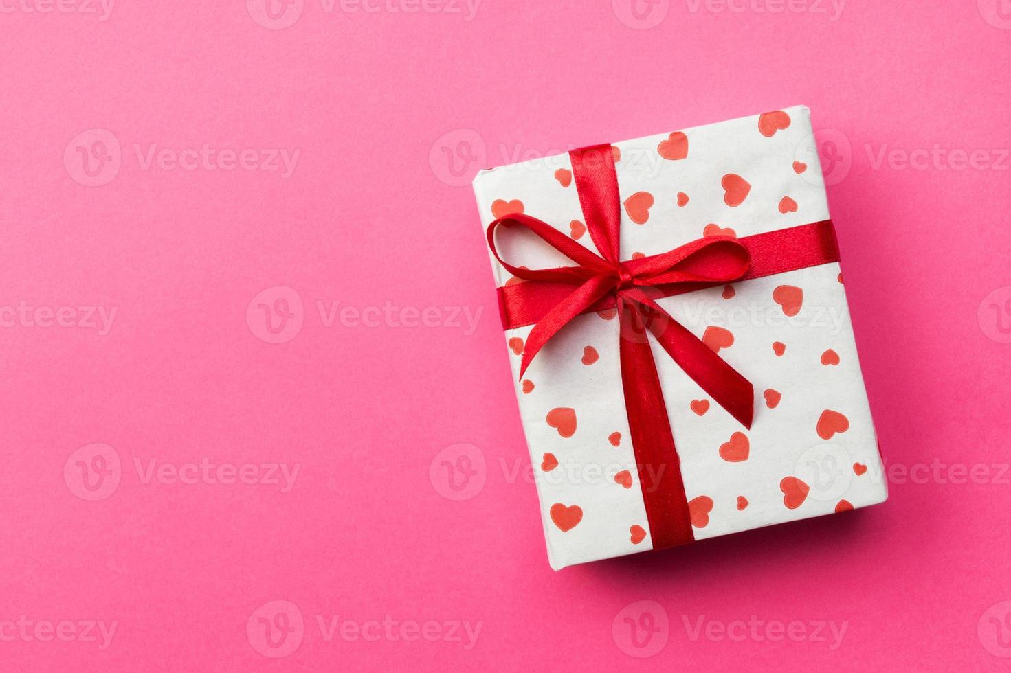 Background with gift box and hearts on pink Background. Top view with copy space for text photo