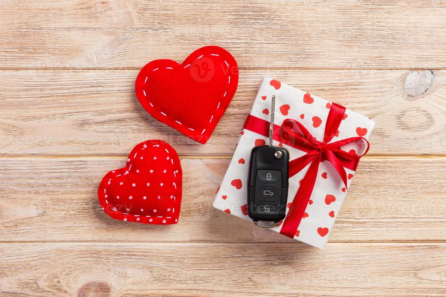 Valentine or other holiday handmade present in paper with red hearts, car keys and gifts box in holiday wrapper. box gift on orange wooden table top view with copy space, empty space for design photo