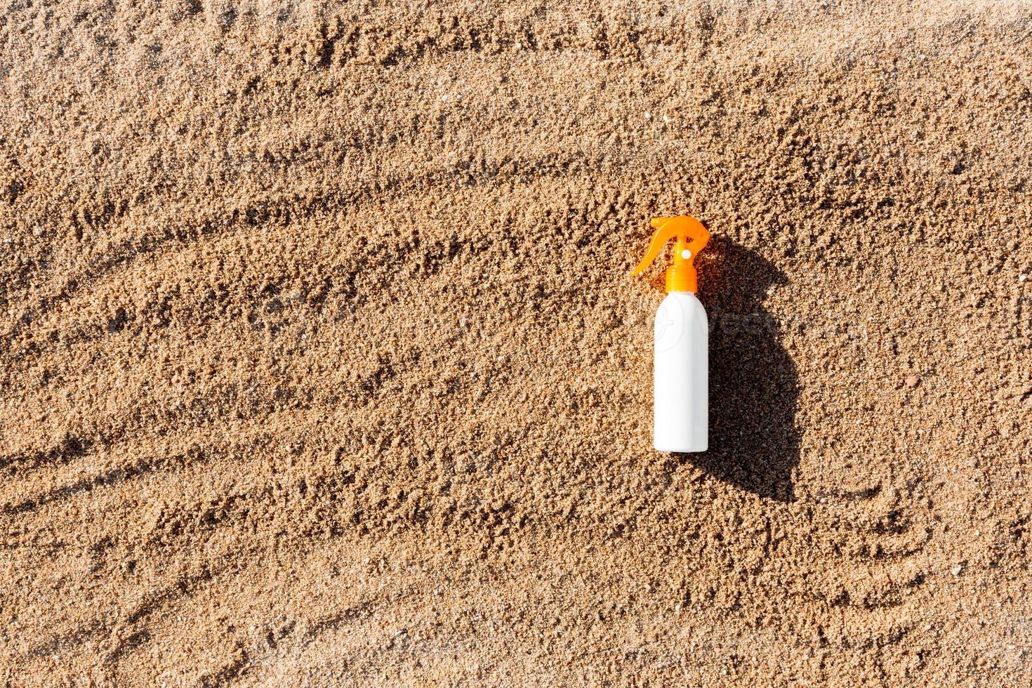 Suntan lotion white bottle on sand with copy space. sunblock spf cream on the sea beach in summer vacation concept photo