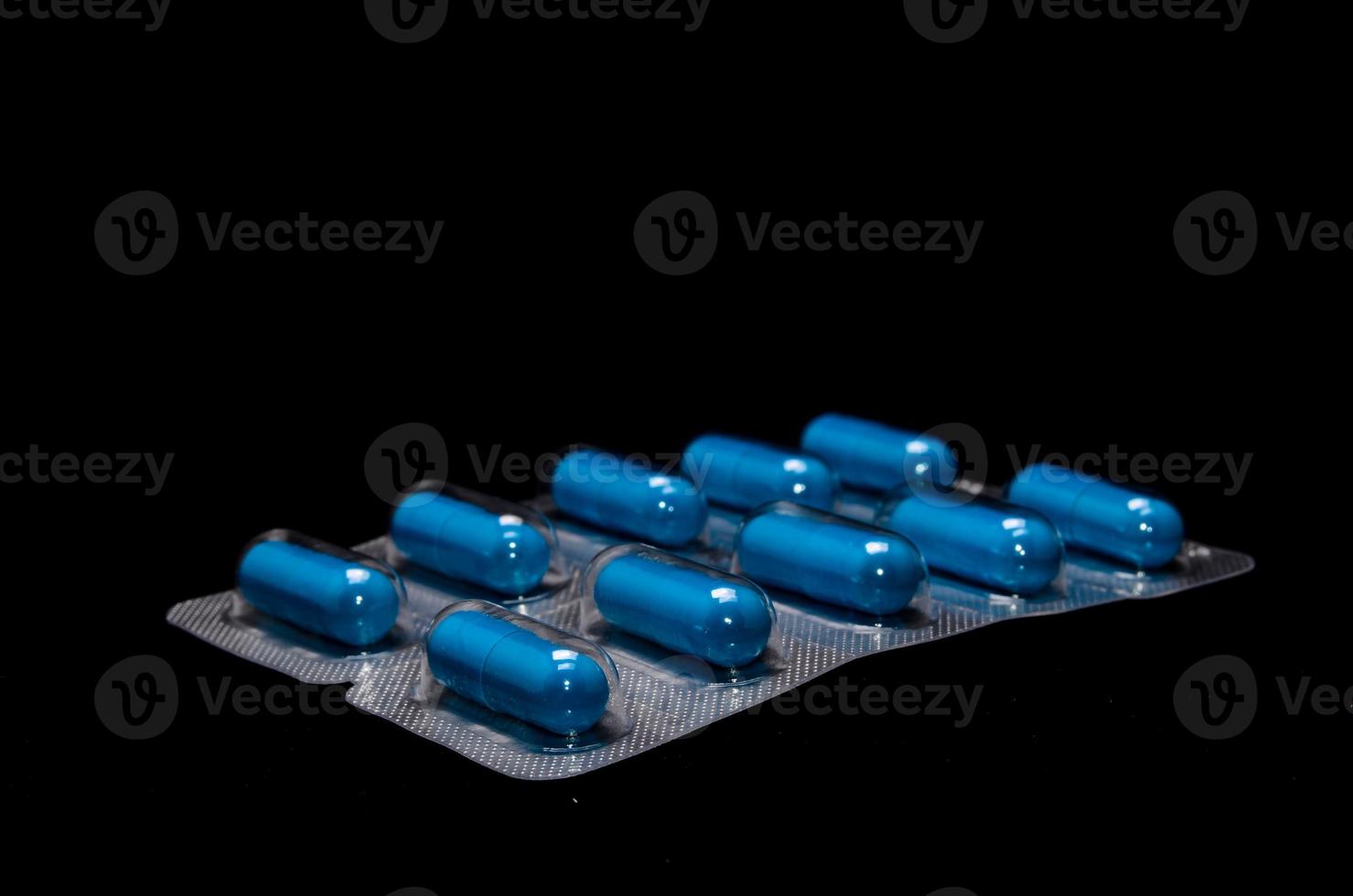 Blue capsules on black background photo