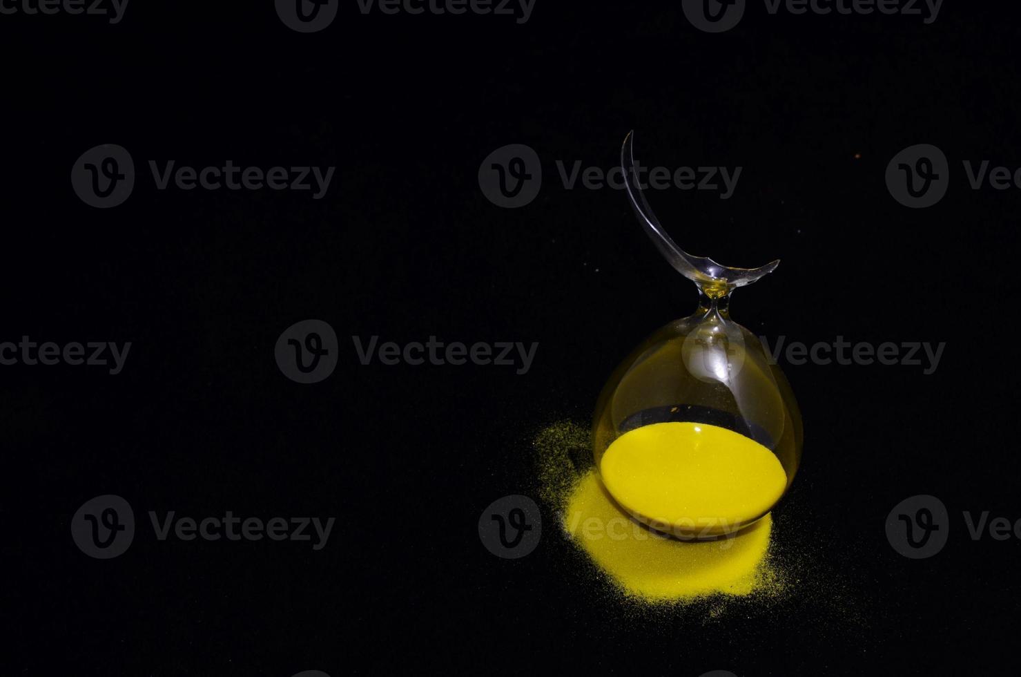 Broken hourglass on dark background photo