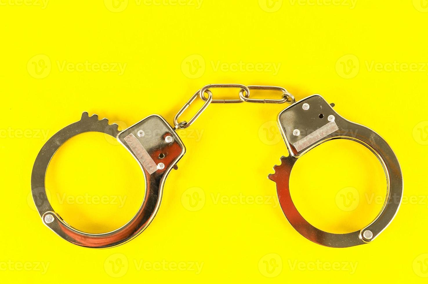 Isolated handcuff on yellow background photo