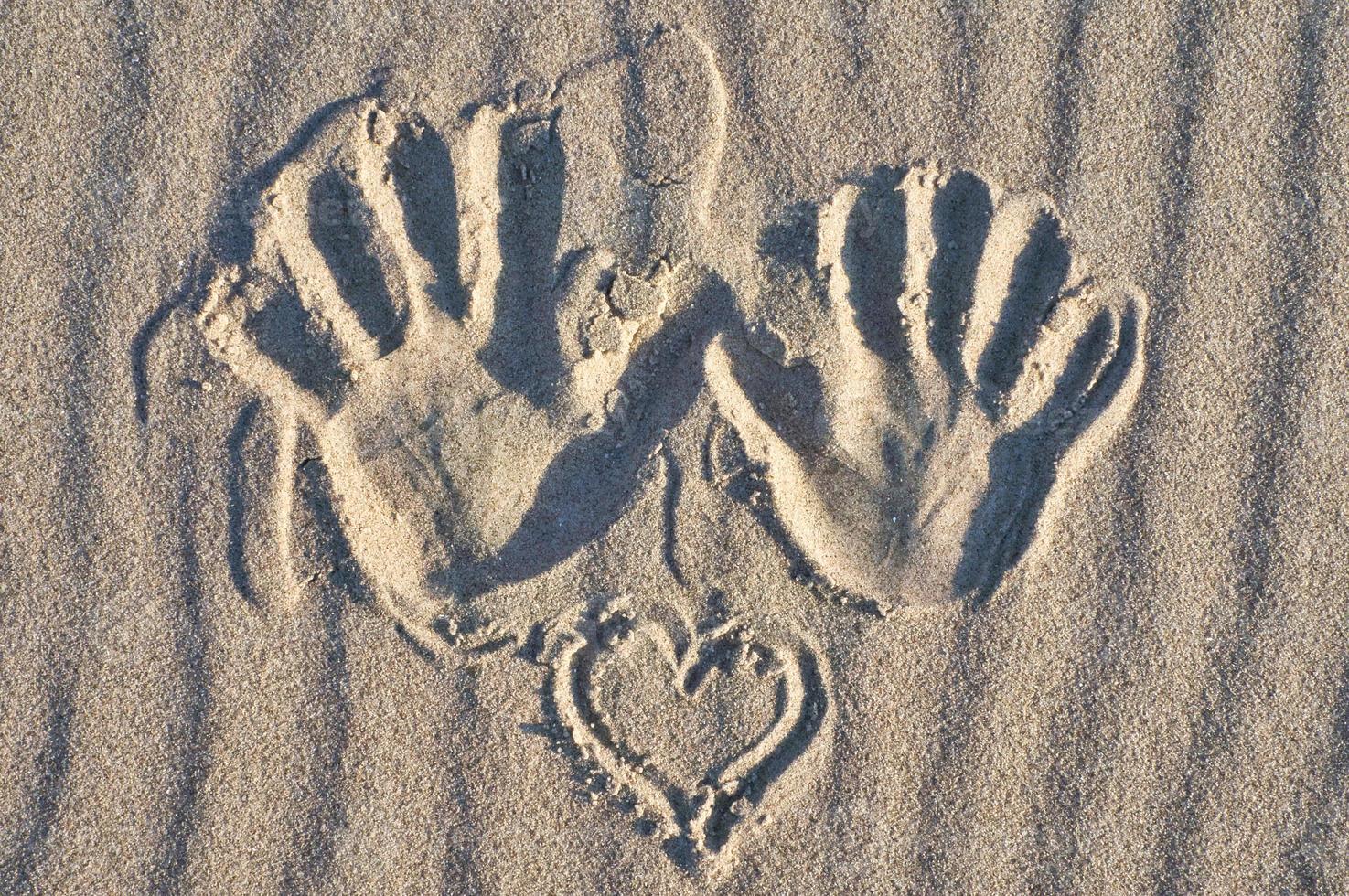 Hand print with heart in the sand on the beach. Wavy sand. Still life on the seashore photo