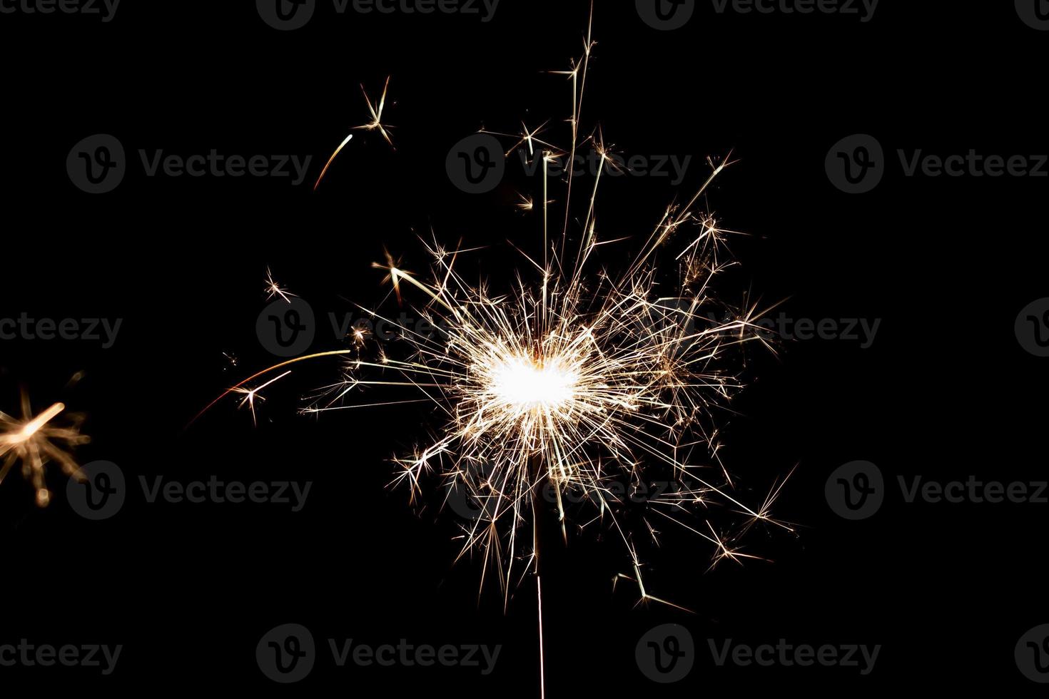 Burning sparkler isolated on black background. Fireworks theme. Light effect and texture. photo