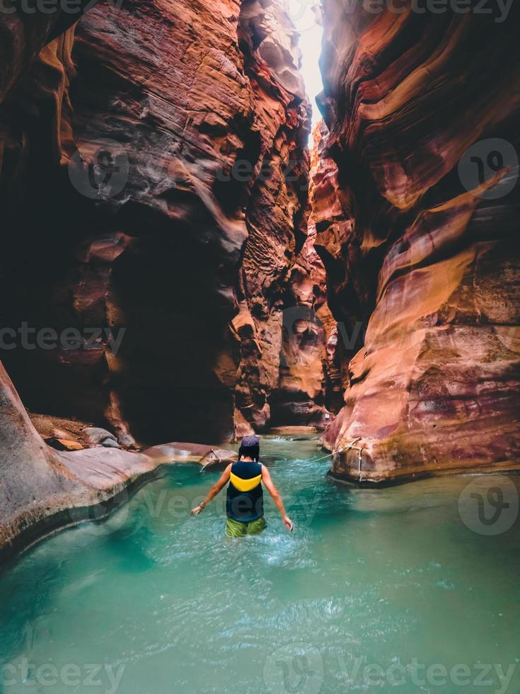 Female tourist walk in water in famous river canyon of Wadi Mujib in amazing golden light colors. Wadi Mujib travel destination in Jordan photo