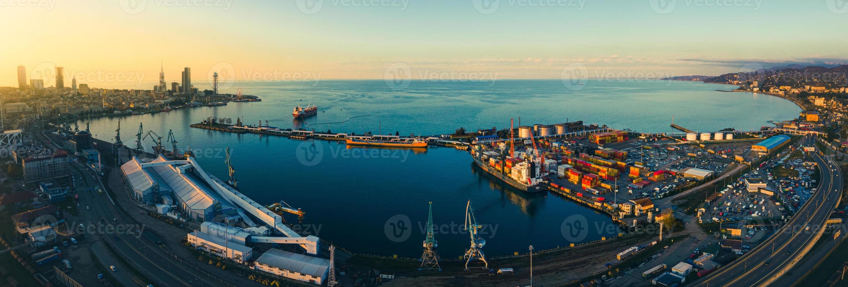 vista aérea de transporte de carga en batumi con ferrocarril y carretera con automóviles, puerto panorámico y paseo marítimo con puesta de sol sobre los rascacielos del horizonte. Georgia foto