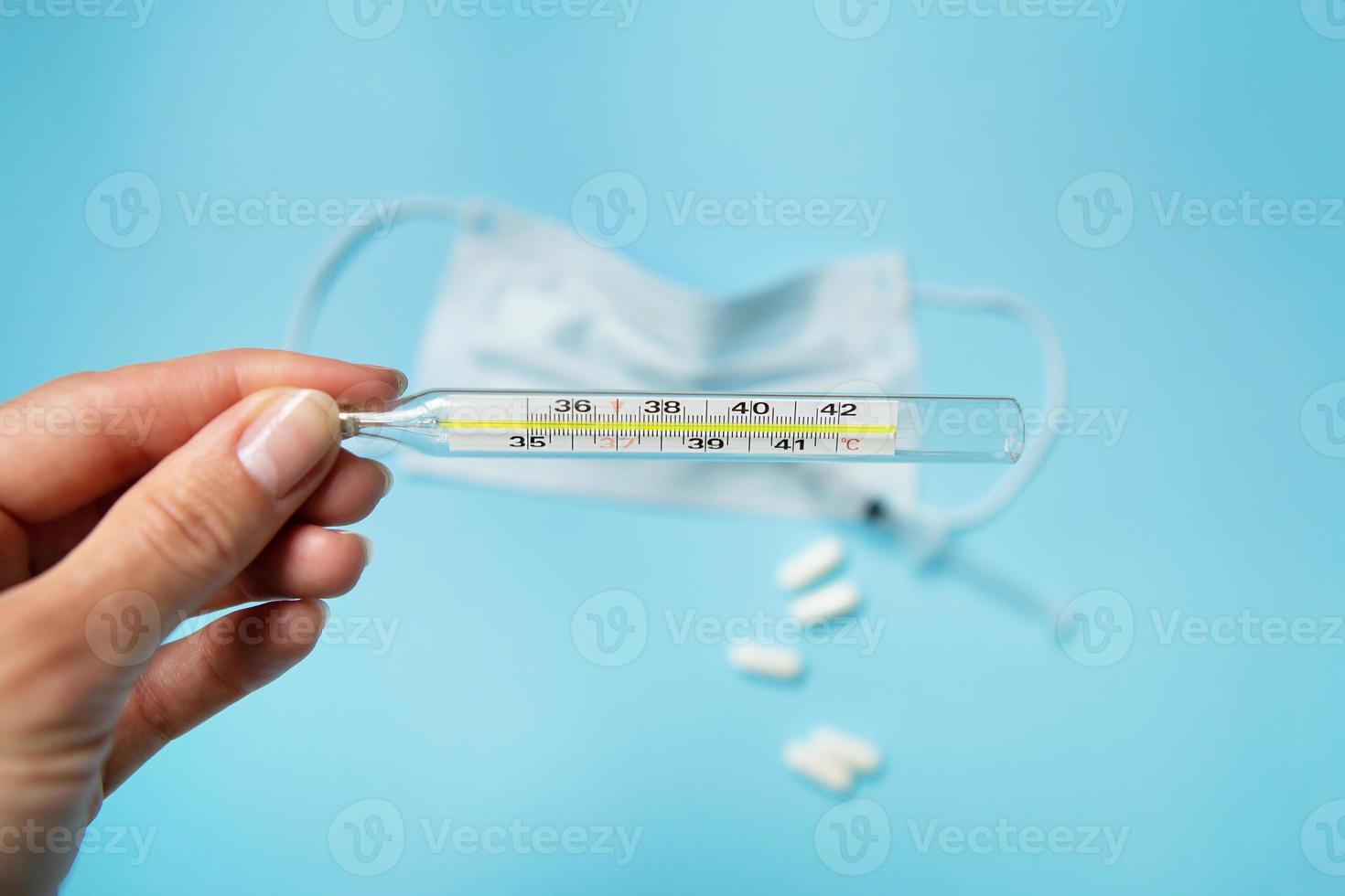 The hand holds a thermometer showing the patient's body temperature photo
