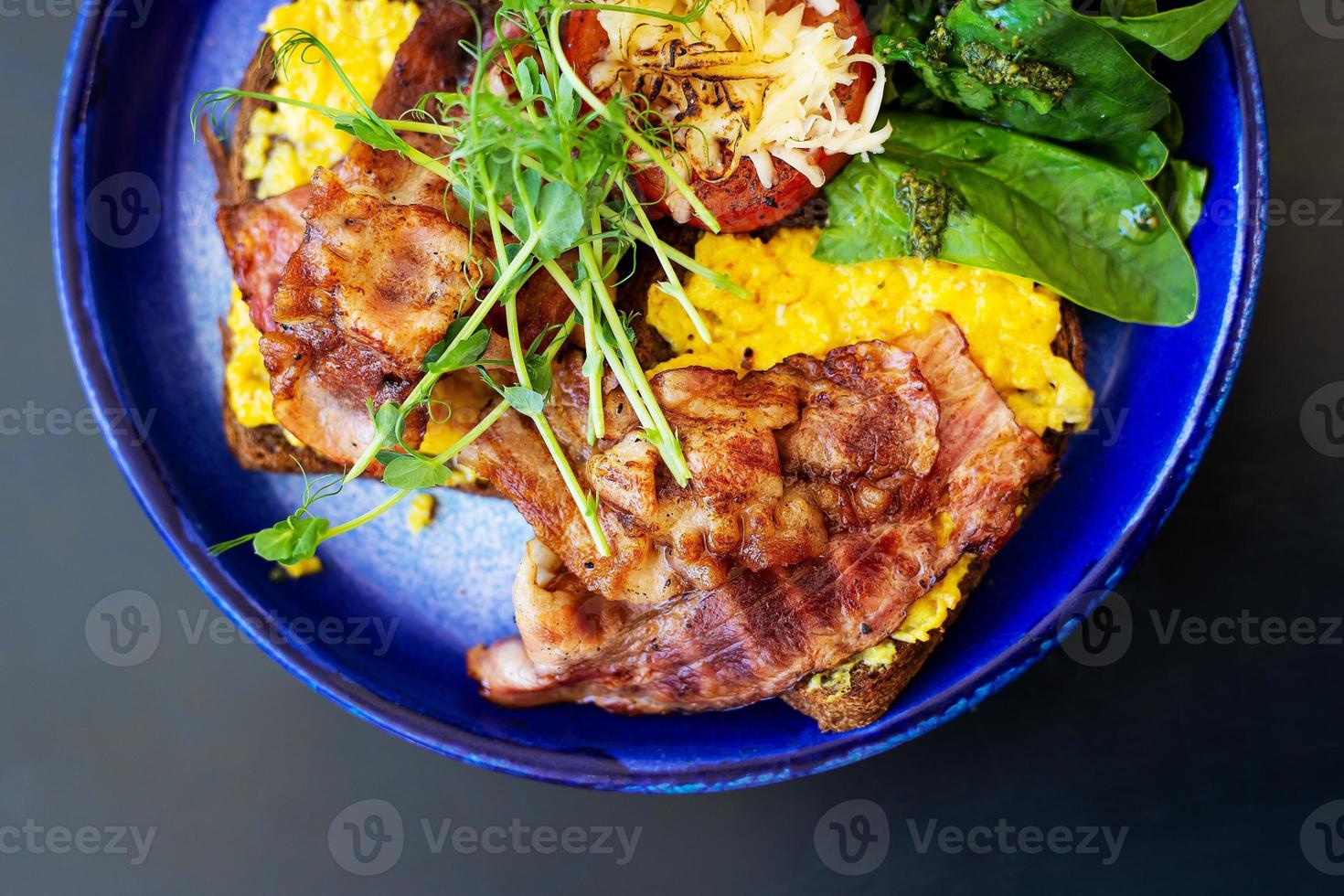 Very bright and healthy breakfast on a plate - bacon, egg, salad, tomato, cheese, a glass of yogurt. Close-up, top view. photo