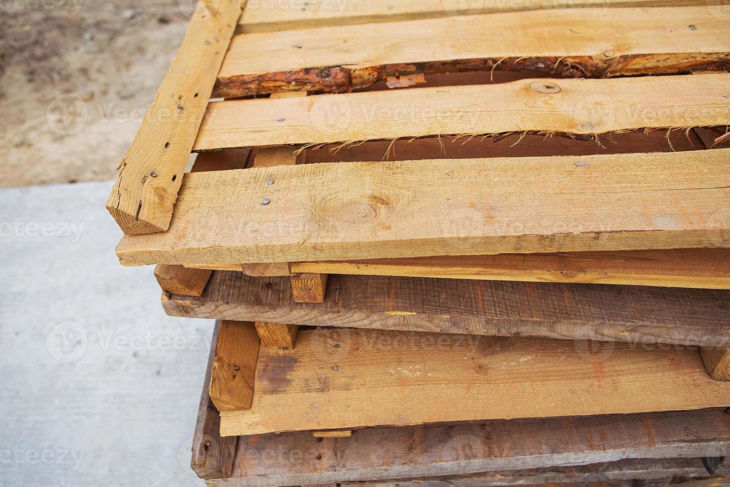 A lot of old wooden pallets stand on the street on top of each other, all for repair. photo