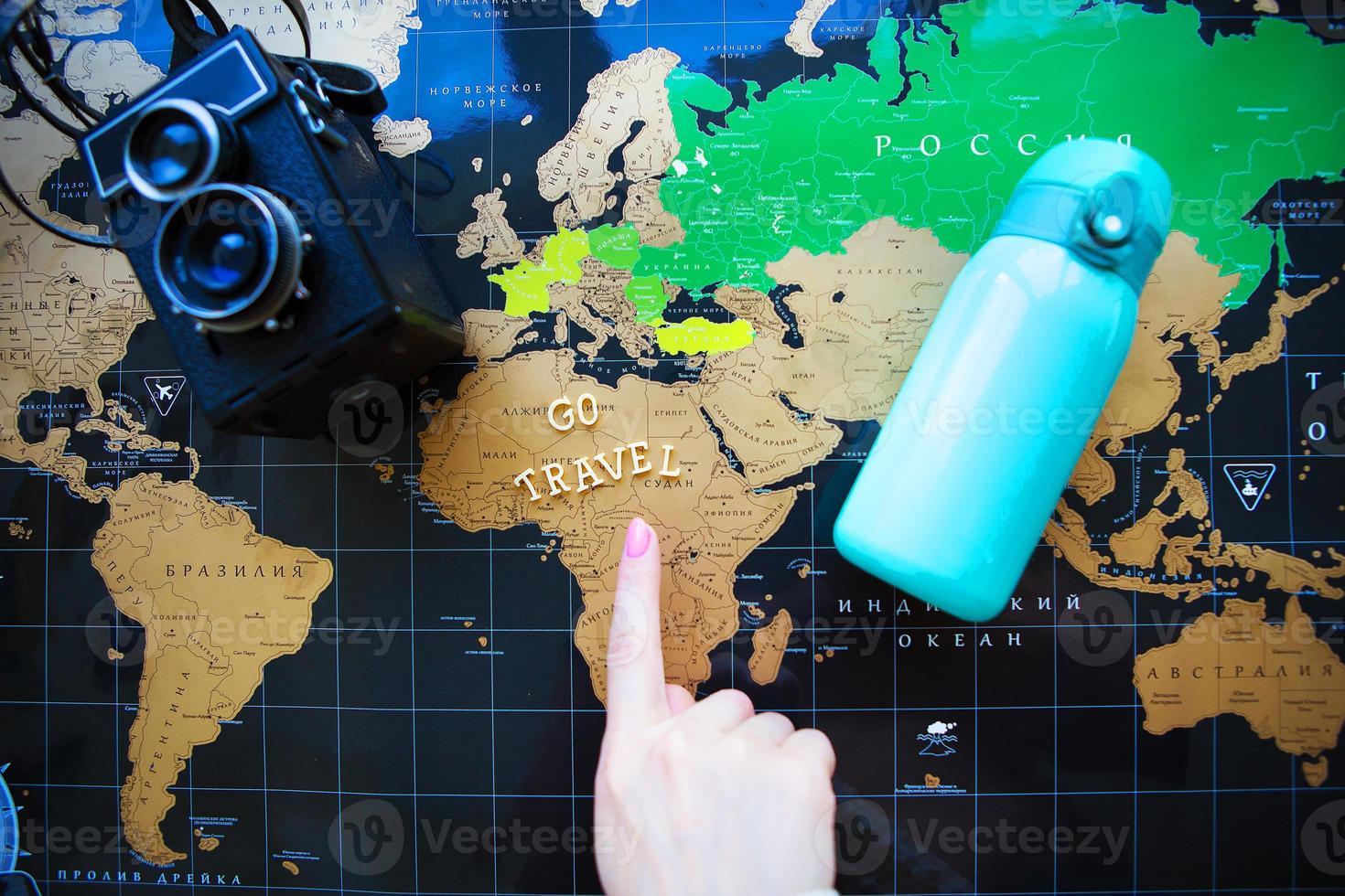 Map of the world in Russian. The finger of the girl points to different corners of the world. photo
