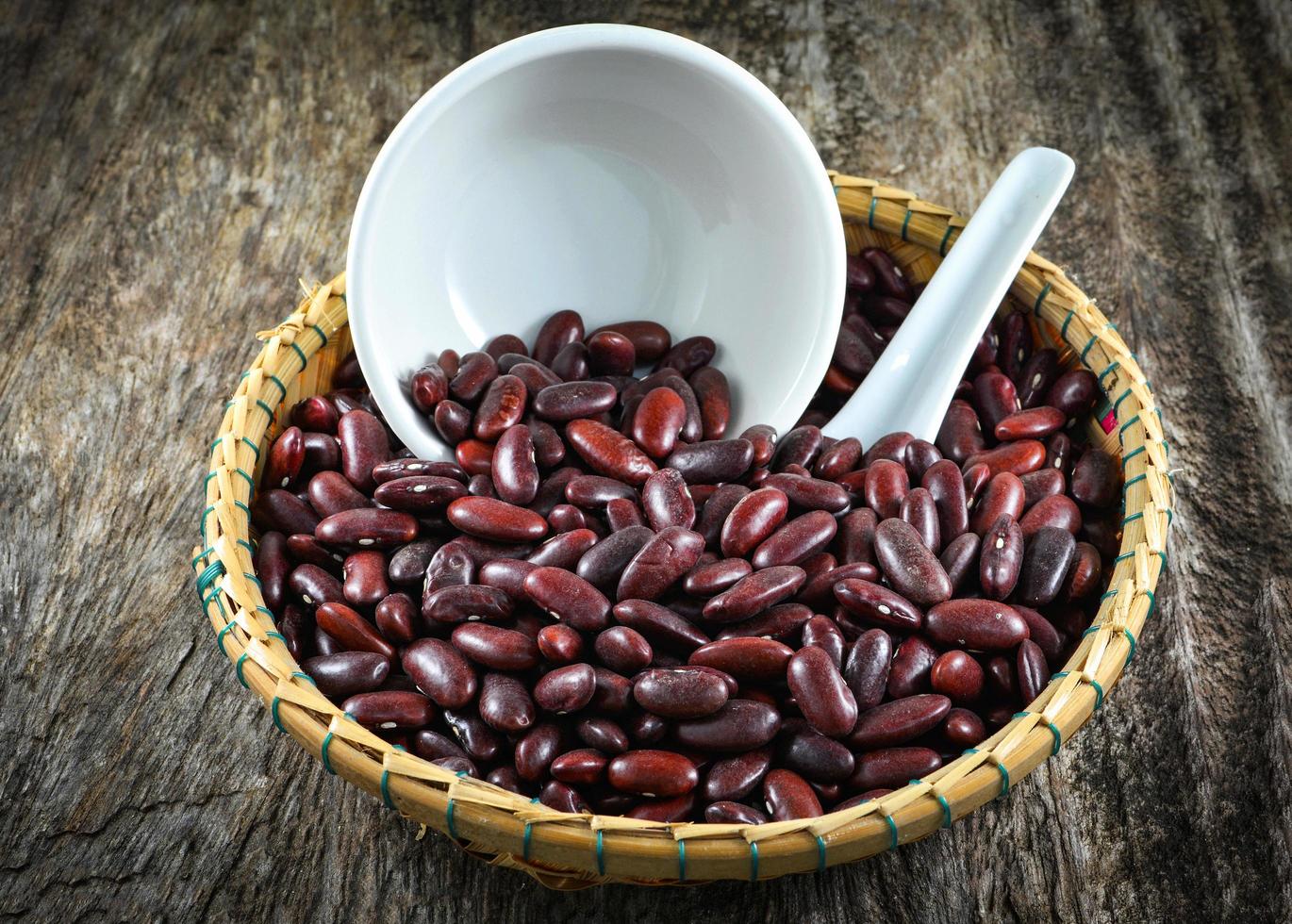 frijoles rojos azuki o semilla de grano de frijol rojo en la cesta y cuchara de taza foto