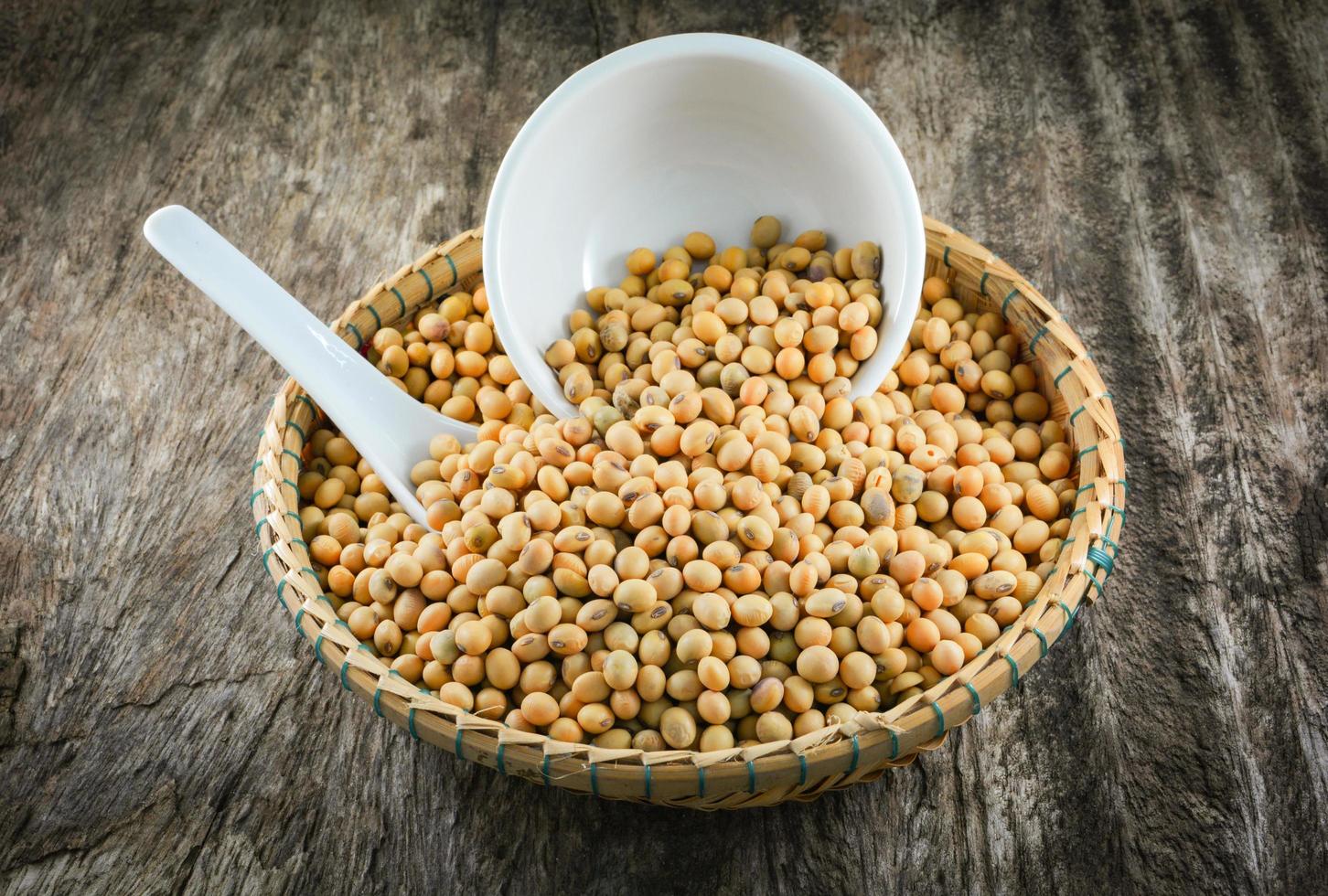 soybeans or soya beans grain seed on bamboo basket white cup and spoon on rustic wood background photo