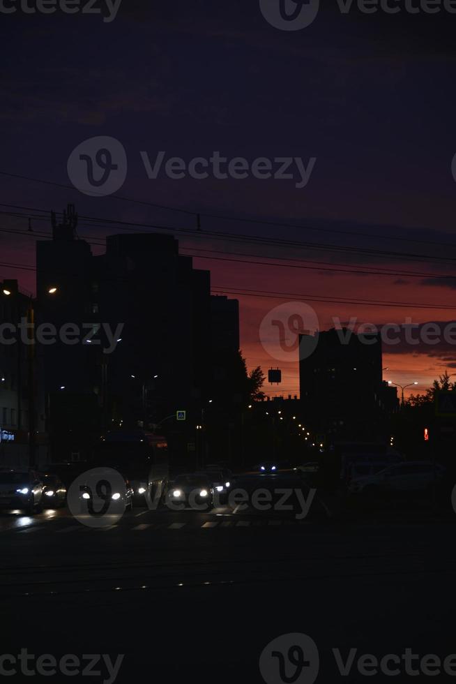 Pink bright sunset and cars on the road. Roofs of houses and a bright sunset. photo