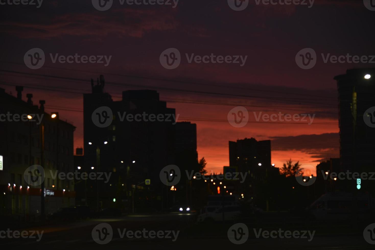 puesta de sol rosa brillante y coches en la carretera. techos de casas y una brillante puesta de sol. foto