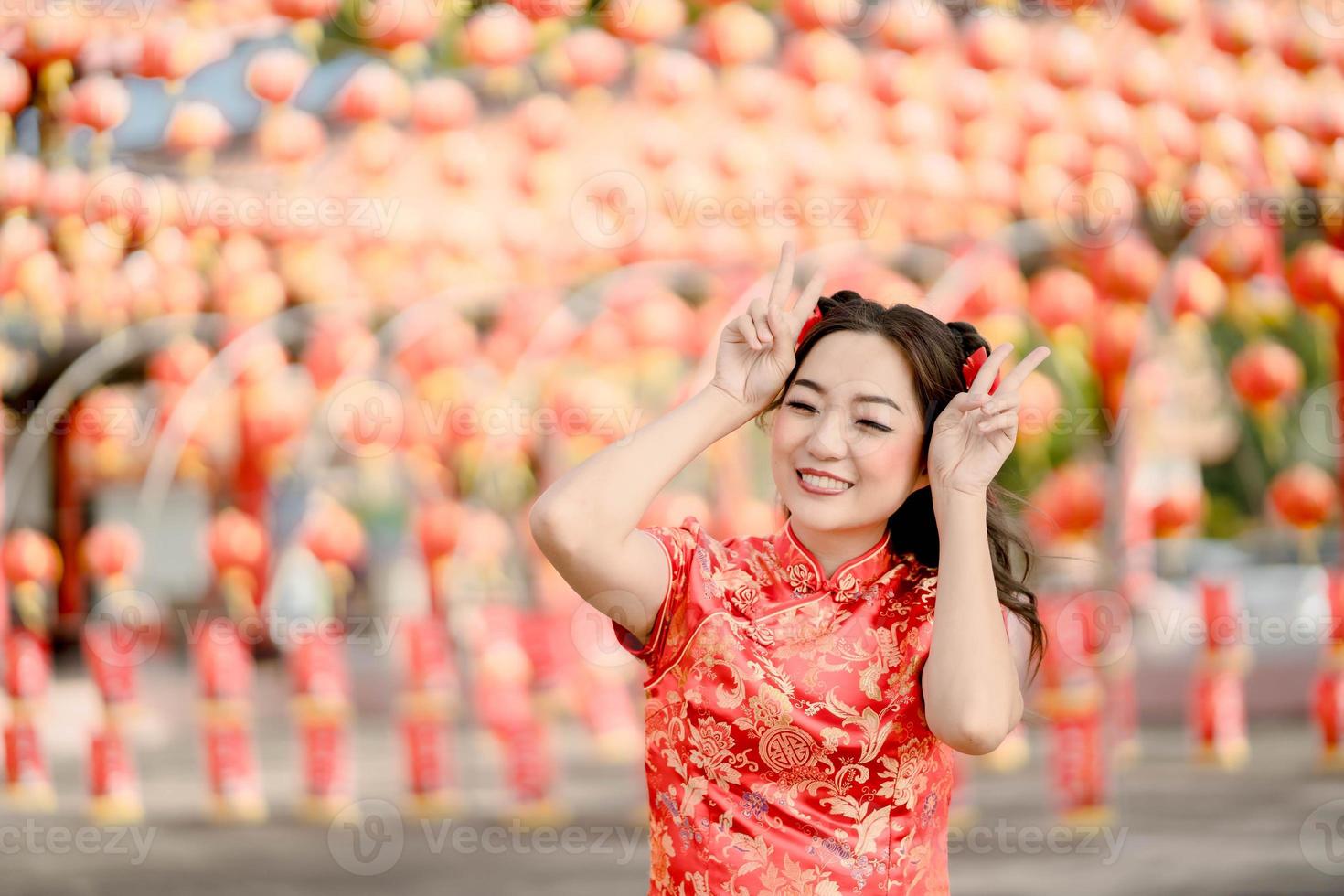 feliz Año Nuevo Chino. mujer asiática con vestido tradicional cheongsam qipao posando conejo en el templo budista chino. celebrar el año nuevo lunar chino, vacaciones de temporada festiva. foto