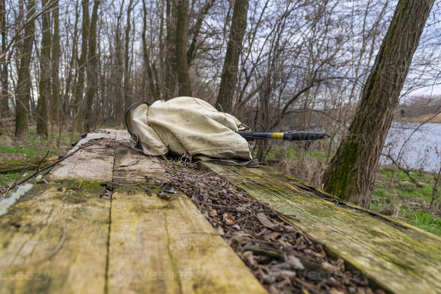 Fishing backpack with a fishing rod on an old table in nature photo