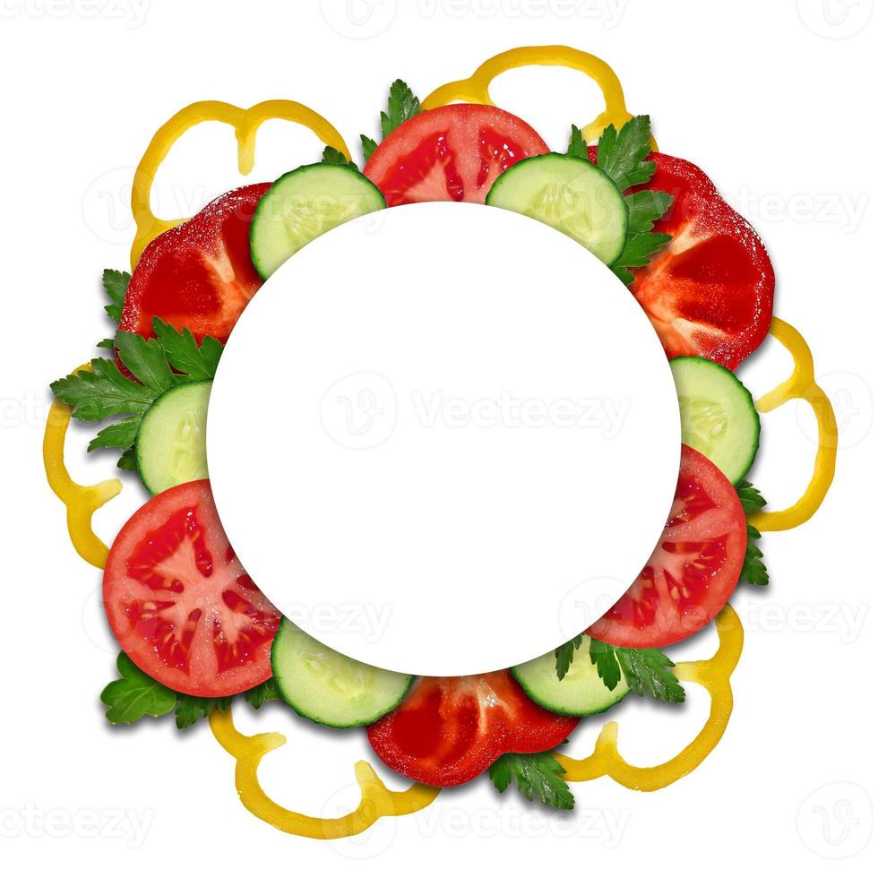 un círculo de pimientos amarillos y rojos, tomate, pepino, perejil con una hoja redonda en el medio sobre un fondo blanco. vegetales picados ingredientes para ensalada foto