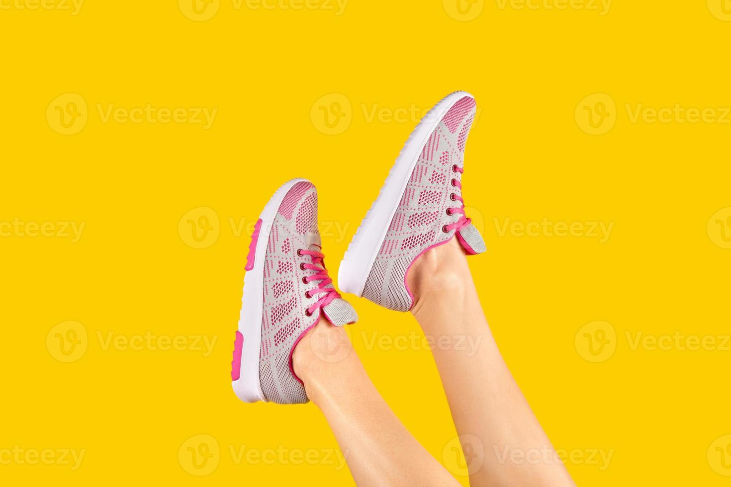 esbeltas piernas femeninas en zapatillas de deporte de moda rodadas sobre un fondo amarillo. publicidad de calzado. concepto de venta de verano. elemento de diseño foto