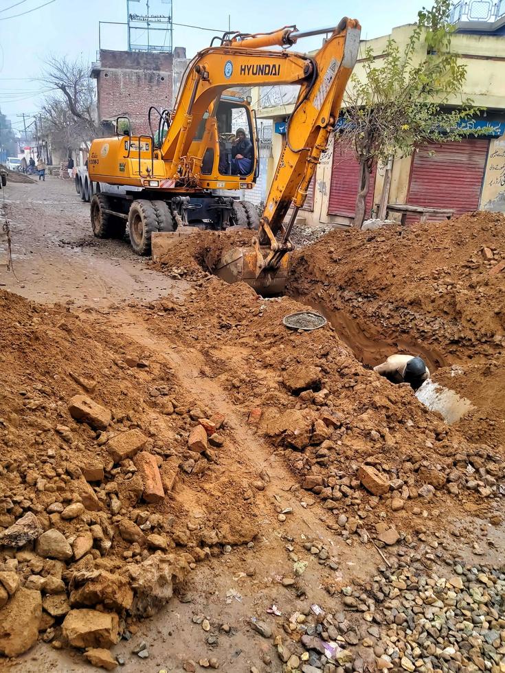 Excavator digs a large trench for pipe laying. Backhoe during earthmoving at construction site. Earth-moving heavy equipment photo