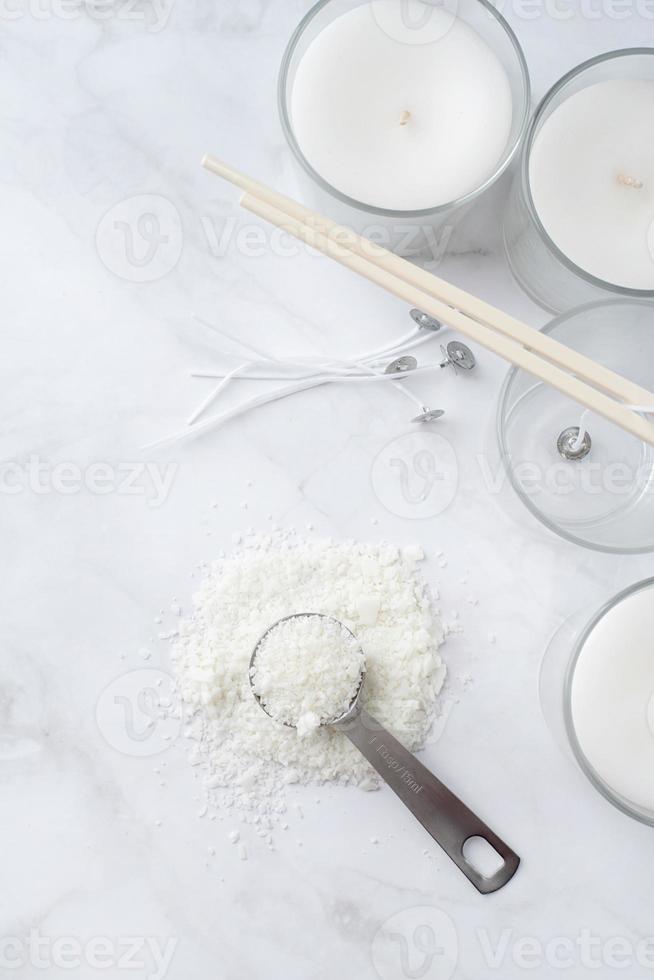ingredients for candle making , soy wax flakes, candles, wicks on light marble background
