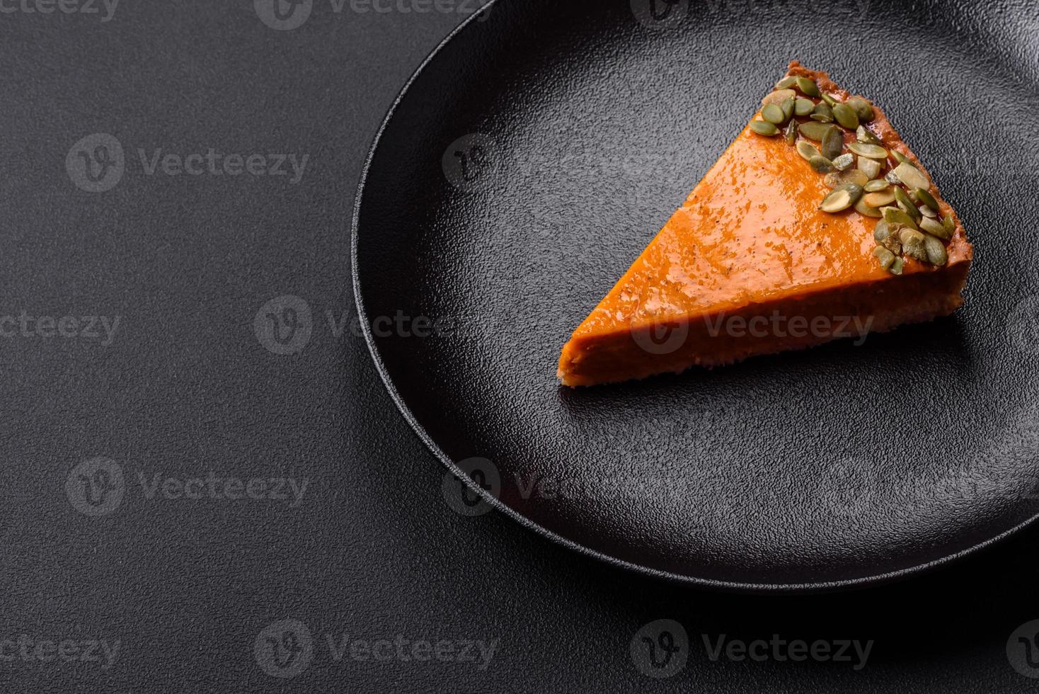 Beautiful tasty pumpkin pie with slices on a black ceramic plate photo