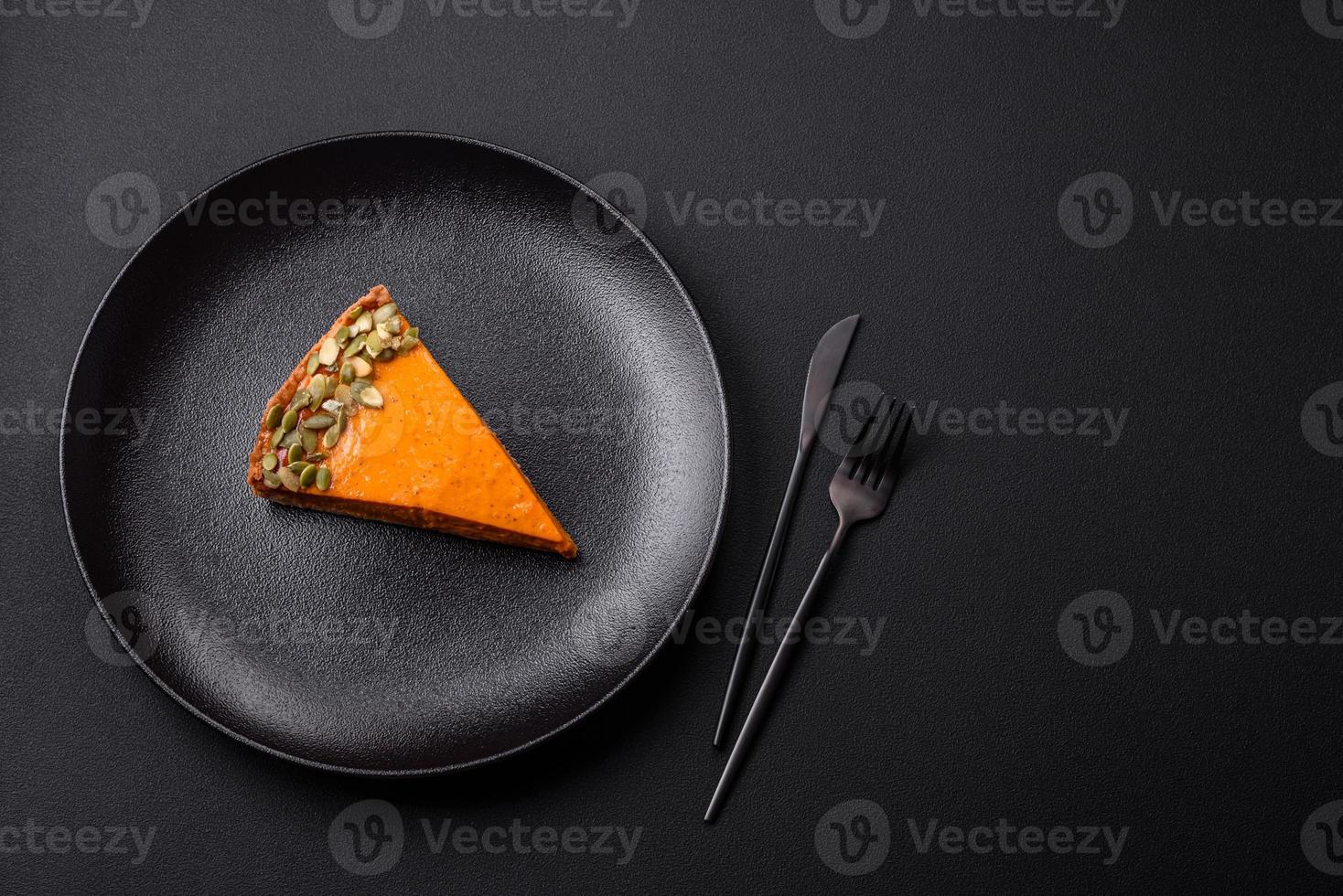 Beautiful tasty pumpkin pie with slices on a black ceramic plate photo